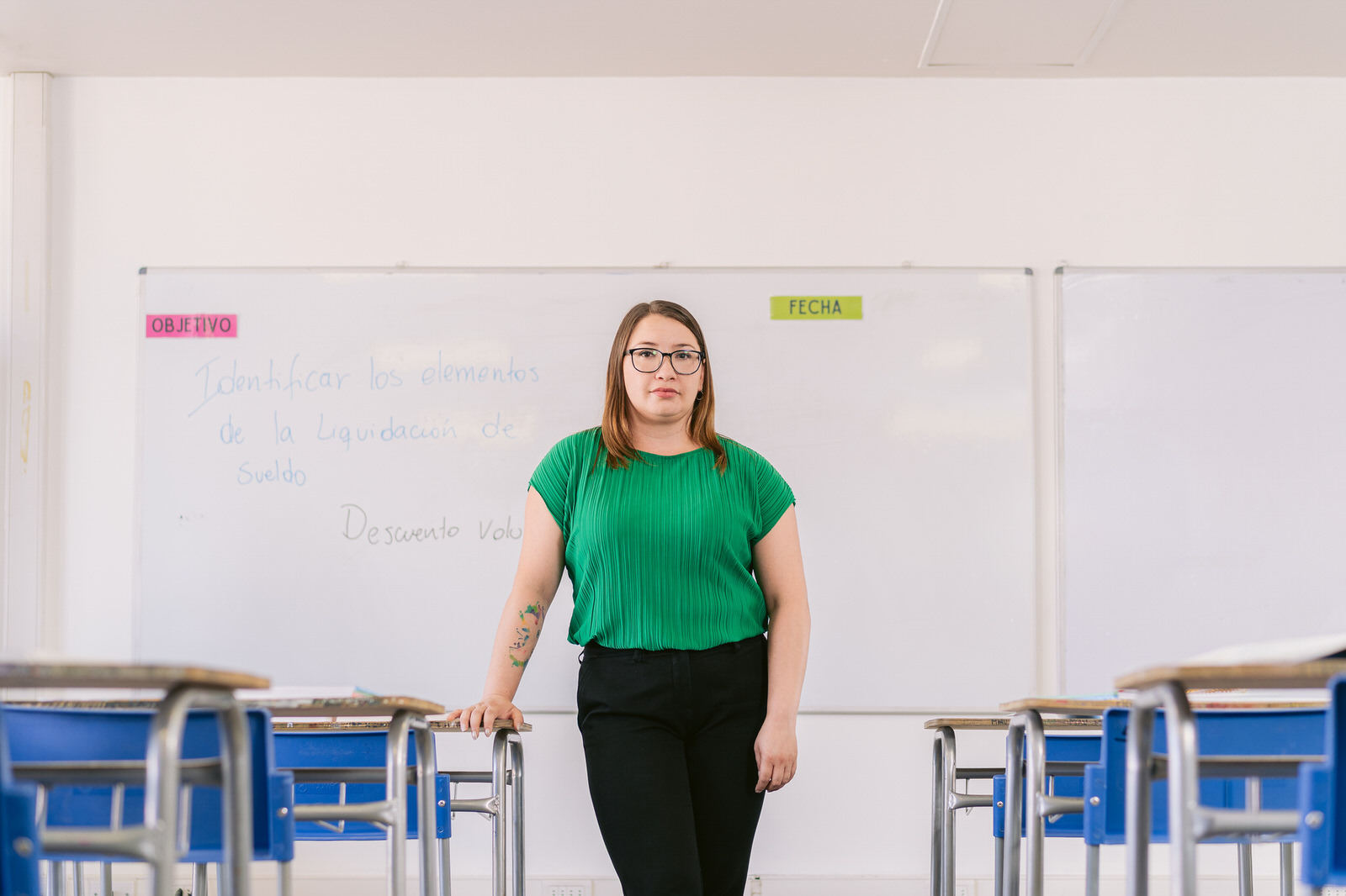 Profesora de pie junto a pizarra en aula — campaña Elige Educar Mineduc